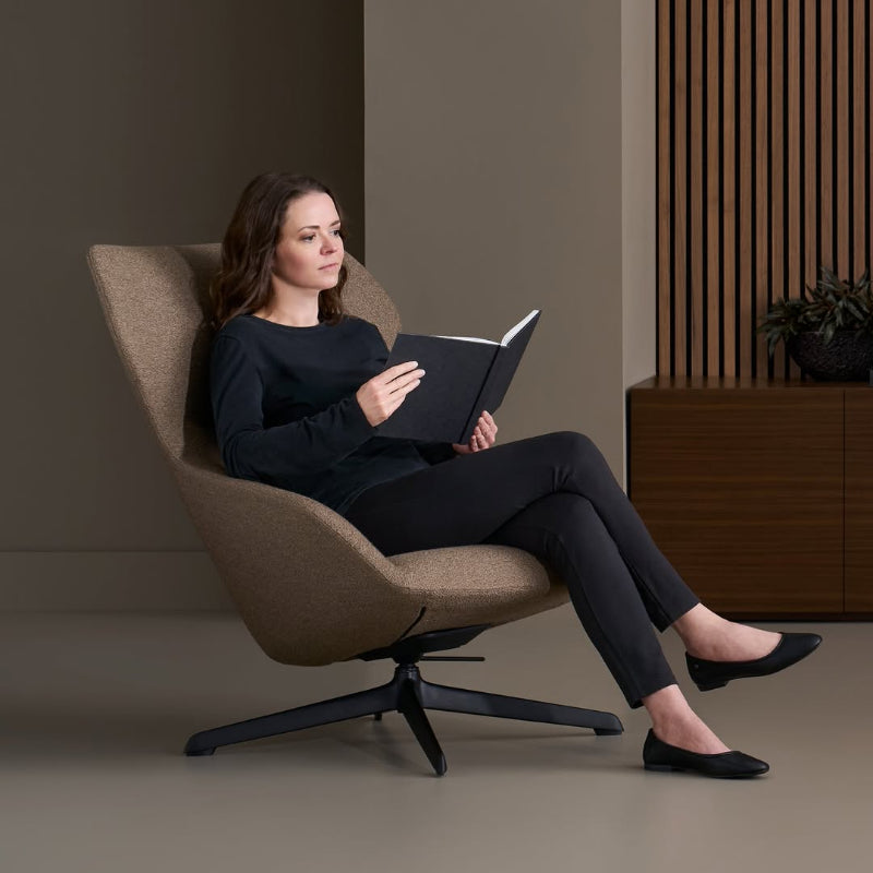 Woman reading a book in a modern chair in a minimalistic room.